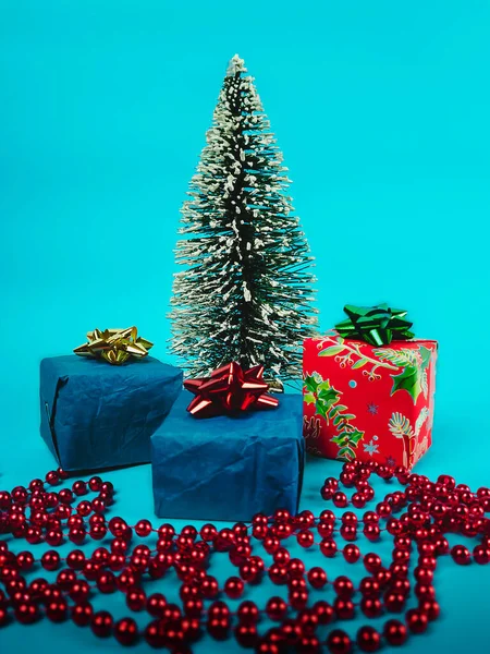 Mavi arka planda hediyeler ve süslemeler olan Noel ağacı.