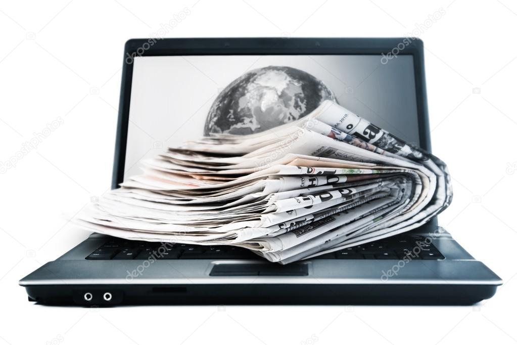 Online magazines -Stack of magazines next to a laptop