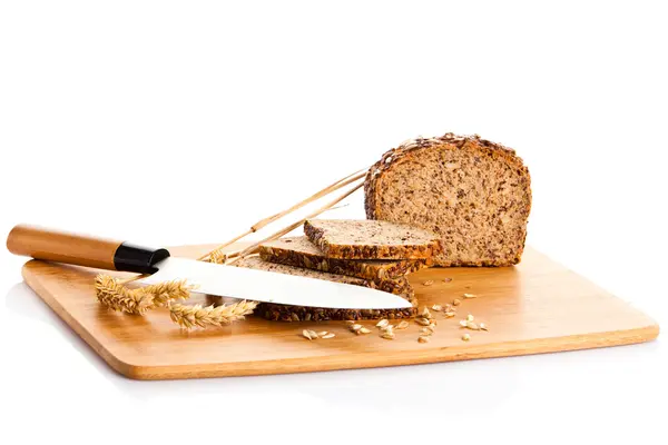 ขนมปังโฮลเมดตัดเป็นชิ้นๆบนกระดานขนมปังไม้ — ภาพถ่ายสต็อก
