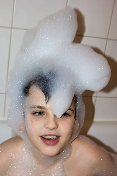 Enfant autiste dans une casquette de savon de mousse souriant fils créatif chapeau de — Photo