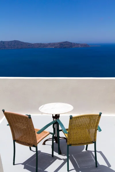 Стол и стулья с видом на ясный день на Санторини, Греция — стоковое фото