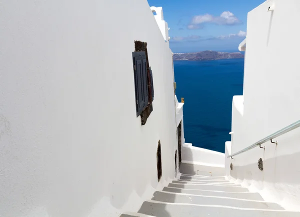 Senderos coloridos y blancos como calles estrechas y el mar de caldera en el fondo en Santorini, Grecia Fotos de stock libres de derechos