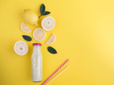 Sarı arka planda cam bir şişede limonlu smoothie manzarası. Boşluğu kopyala.