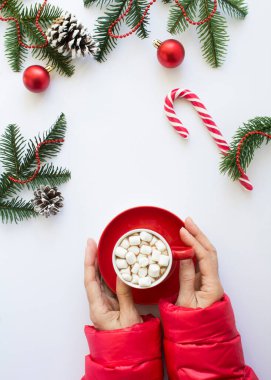 Beyaz arka planda kırmızı bardakta sıcak çikolata olan kadın elleri. Noel kompozisyonu. Üst Manzara. Konum dikey.