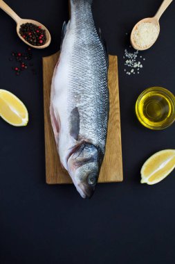 Siyah arka plandaki kesme tahtasındaki balık deniz kabuğunun en üst görüntüsü. Uzayı kopyala Konum dikey.
