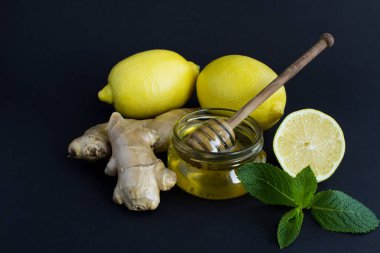 Limona yakın çekim, zencefil ve bal siyah arka planda. Çay için malzemeler. Yakın plan..