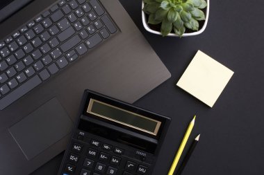 Bilgisayarlı, hesap makineli ve siyah arka planlı ofis masasının üst görüntüsü. Yakın plan. Çalışma masasının düz uzantısı.