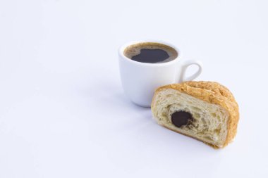 Kahve fincanına yakın plan ve beyaz arka planda çikolatalı kruvasan. Boşluğu kopyala.