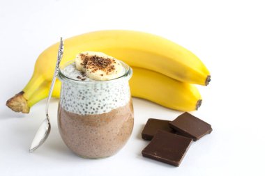 Beyaz arka planda cam kavanozda chia tohumu ve muz olan çikolatalı puding. Yakın çekim..