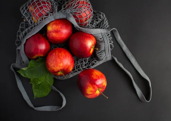 Mesh Einkaufstasche Mit Roten Äpfeln Auf Schwarzem Hintergrund Kein Plastiktütenkonzept lizenzfreie Stockfotos