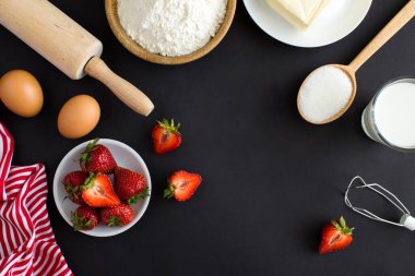 Siyah arka planda çilekli turta ya da pasta yapmak için en iyi malzeme. Boşluğu kopyala.