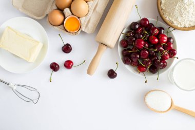Beyaz arka planda vişneli turta ya da pasta yapmak için malzemelerin üst görüntüsü. Boşluğu kopyala.