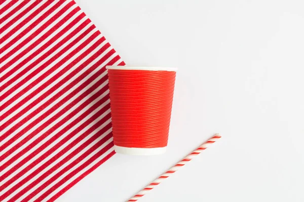 Sıfır kayıp. Tek kullanımlık kırmızı kağıt bardak ve beyaz arka planda saman içmek. Üst Manzara. Boşluğu kopyala.