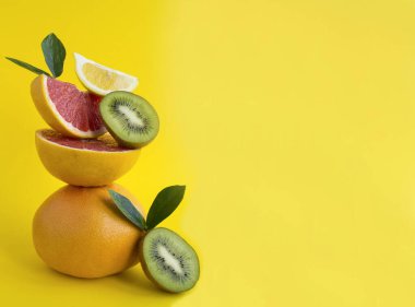 Greyfurt, limon ve kivi piramidi sarı arka planda dengede. Uzayı kopyala Yakın çekim..