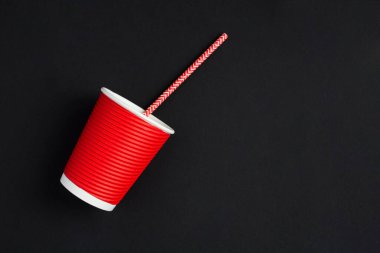 Sıfır kayıp. Tek kullanımlık kırmızı kağıt bardak ve siyah arka planda saman içmek. Üst Manzara. Boşluğu kopyala.