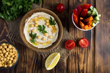 Kasede humus manzarası ve kırsal ahşap arka planda sebze. Yakın çekim..