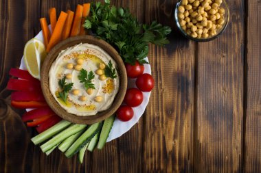Kasede humus ve tahta arka planda sebze manzarası. - Yakın çekim. Boşluğu kopyala.
