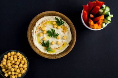Kasede humus ve siyah arka planda sebze manzarası. - Yakın çekim. Boşluğu kopyala.