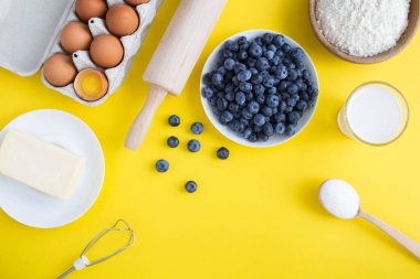 Sarı arka planda yaban mersinli turta ya da kek yapmak için en iyi malzeme. Boşluğu kopyala.