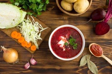 Beyaz kasede pancar çorbası ve ahşap arka planda malzeme. Ukrayna yemeği. Boşluğu kopyala.