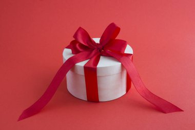 Wooden gift box with tied red bow on the red background. Closeup.