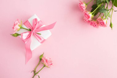 Gift box and pink roses on the pink  background.Top view. Copy space.