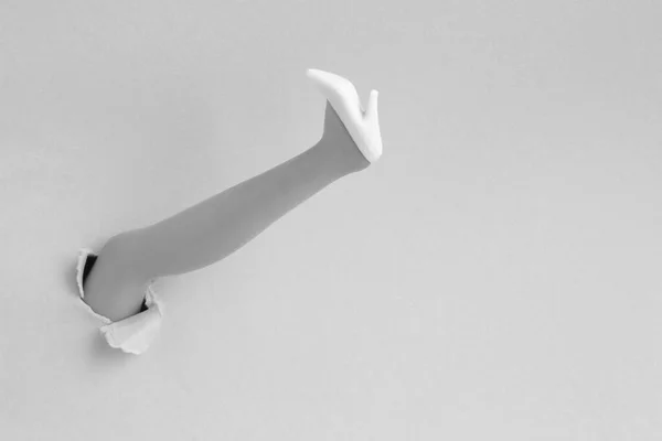 Female Foot White Shoe Inserted Hole Torn Paper Gray Background — ストック写真