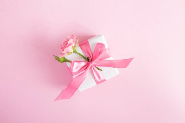 Gift box with pink rose on the pink  background.Top view. Copy space.