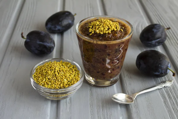 Smoothies with blue plums and  bee pollen on the gray wooden background. Close-up.