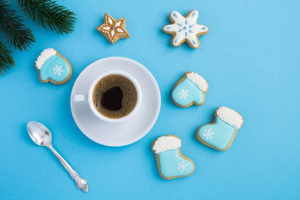 Christmas composition with coffee cup and gingerbread on the blue background. Top view. Copy space.