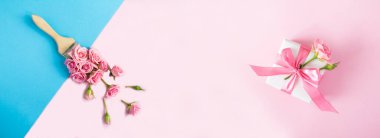 Renkli arka planda pembe güllü boya fırçası ve hediye kutusu. Üst Manzara. Boşluğu kopyala.