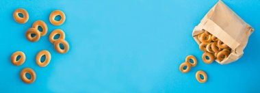 Mavi arka plandaki kağıt pakette simit var. Sancak. Üst Manzara. Boşluğu kopyala.