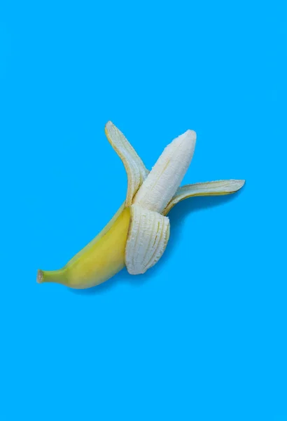 Żółty Obierany Banan Niebieskim Tle Zbliżenie Odbiór Położenie Pionowe — Zdjęcie stockowe