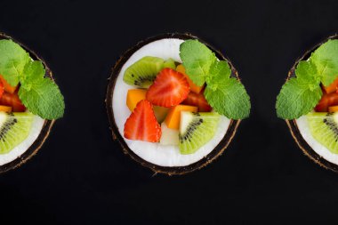 Siyah arka planda yarım hindistan cevizli meyve salatası. Üst Manzara. Yakın plan..