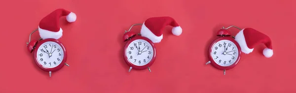 Kırmızı Arka Planda Noel Baba Şapkası Olan Kırmızı Alarm Saati — Stok fotoğraf