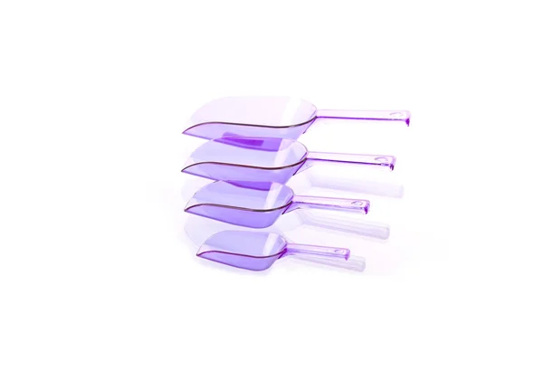 Cuatro cucharadas de plástico de transferencia violeta utilizadas en la cocina, aisladas en blanco — Foto de Stock