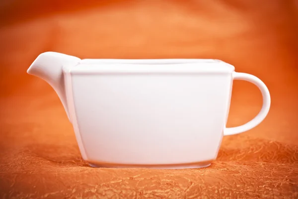 Sauce boat on orange textile background — Stock Photo, Image