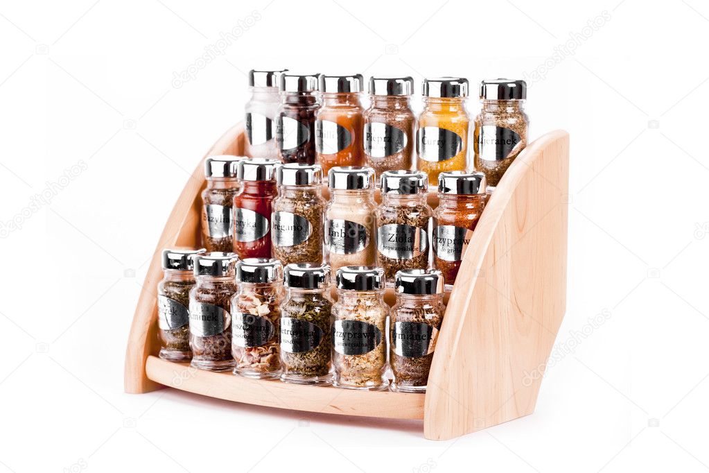 A close up on a spice rack full of a variety of different spices and herb isolated on a white background.