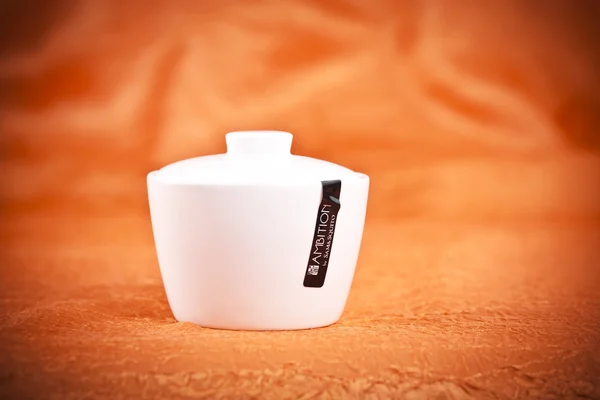 Fine porcelain sugar bowl on orande fabric background — Stock Photo, Image