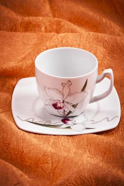 Piccola tazza di caffè a colori su sfondo tessuto arancione — Foto Stock