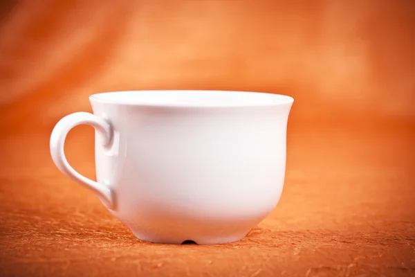 Small color coffee cup on orange fabric background — Stock Photo, Image