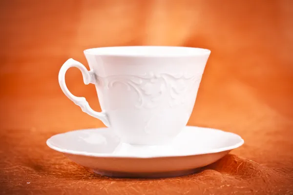 Маленькая чашка кофе на фоне оранжевой ткани — стоковое фото