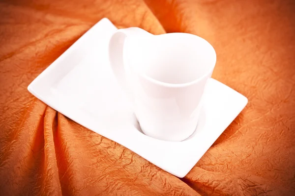 Small color coffee cup on orange fabric background — Stock Photo, Image