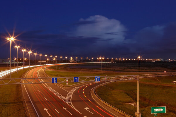 Ringway St Petersburg. Russian road at night, with markings, road signs and lighting masts. The mast lighting on night road. Electric lights in night highway. Road lighting lanterns. Russian roads.
