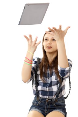 The girl throws in the air tablet PC . Teenage girl in a plaid shirt and short denim shorts, tosses a PC tablet to the top. Girl catches flying in air Tablet PC. Girl, throws up in the air PC tablet clipart