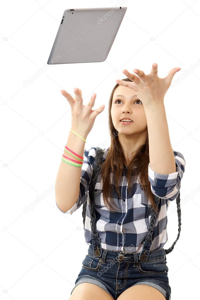 The girl throws in the air tablet PC . Teenage girl in a plaid shirt and short denim shorts, tosses a PC tablet to the top. Girl catches flying in air Tablet PC. Girl, throws up in the air PC tablet