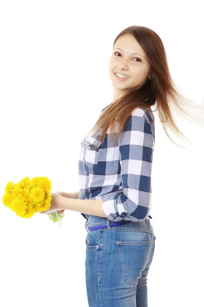 Girl with bouquet yellow wildflowers. Teenage Girl in jeans and a plaid shirt, holding a bouquet of dandelions. — Stock Photo, Image
