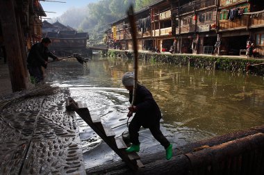 köy zhaohing guizhou Çin nehir: dong etnik kadın nehir köy yüzeyinden enkaz kaldırır, nehirdeki adam setin nehir köy zhaoxing dong Köyü, Nisan 2010 yıkamak için bez yıkar