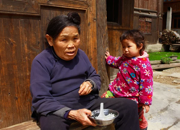 Avó alimenta seu neto na rua perto da casa . — Fotografia de Stock