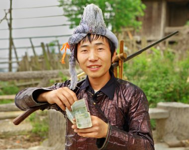 etnik hmong Çince. Guizhou, Çin. tüfek omuzunda, holding adam miao etnik grubu Köyü Festivali, 10 Nisan 2010 Kazanılan para dedi. Basha miao etnik azınlık Köyü, congjiang.